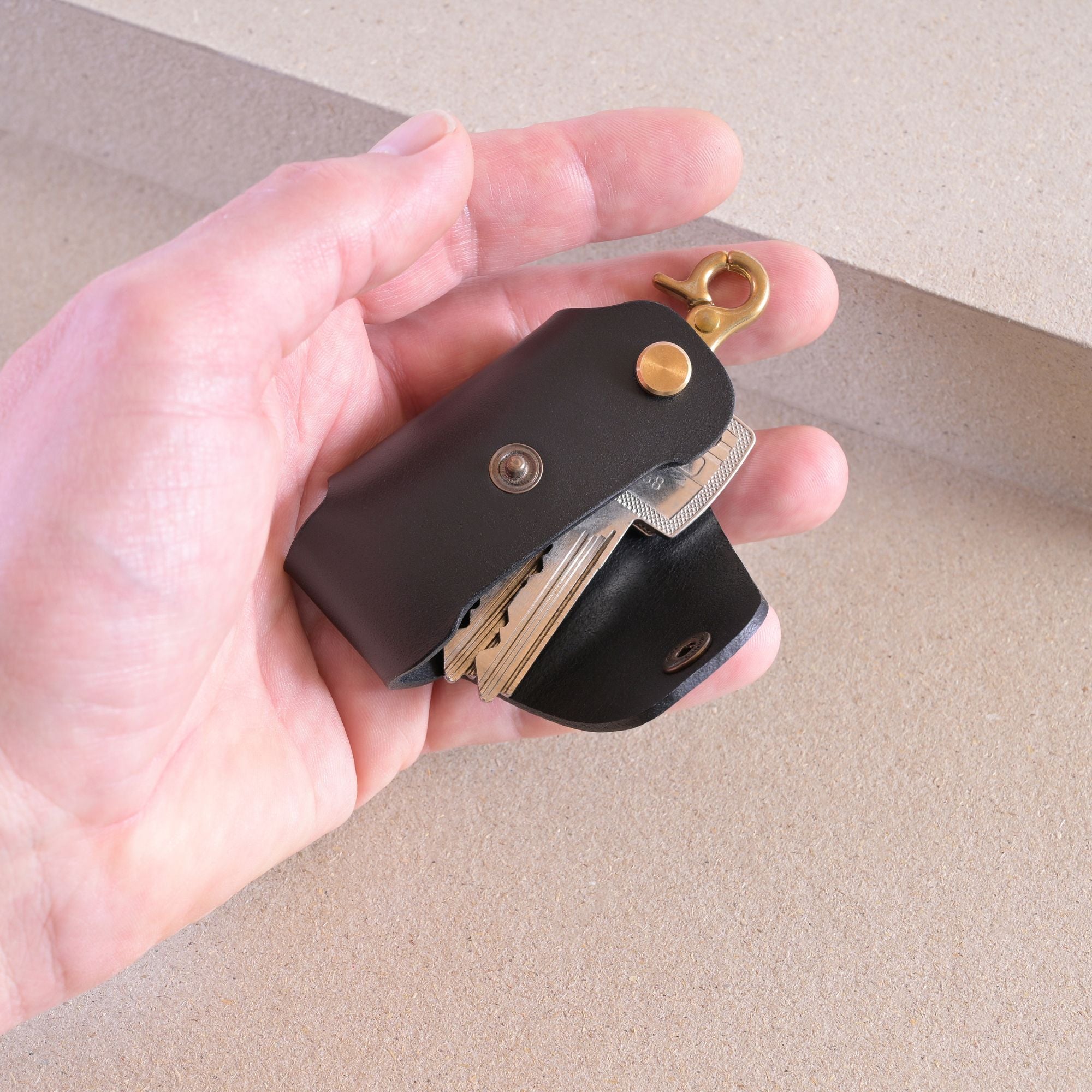 Leather Key Holder in Black with brass clip by Nitmoi, being held in hand